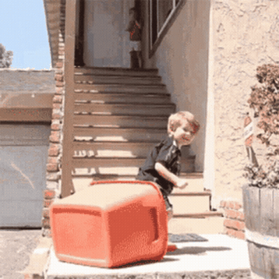 Little Boy Standing On Red Cooler On Porch GIF