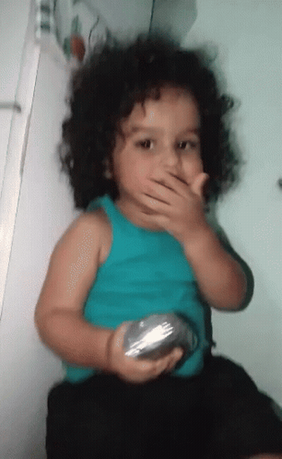 Little Curly Hair Girl Covering Mouth With Silver Object GIF