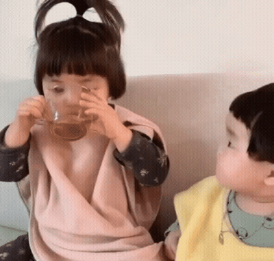Little Girl Drinking From Glass Next To Boy GIF