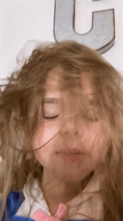 Little Girl Eyes Closed Hair Blowing In Wind In Front Of Letter U GIF