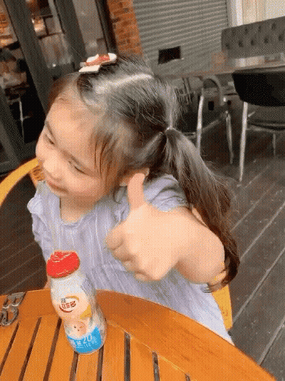 Little Girl Giving Thumbs Up At Table GIF