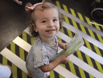 Little Girl Holding Passport On Striped Floor GIF
