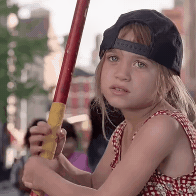 Little Girl In Black Hat Holding Red And Yellow Stick GIF