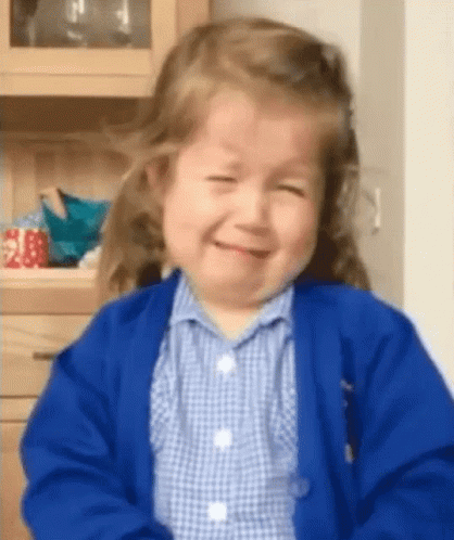 Little Girl In Blue Cardigan And Plaid Shirt Smiling GIF