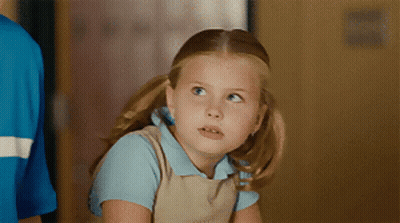 Little Girl In Blue Shirt And Tan Overalls Looking Up GIF