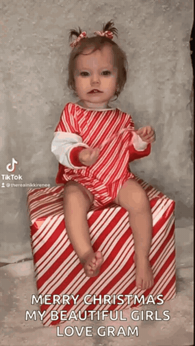 Little Girl In Candy Cane Outfit Sitting On Candy Cane Box GIF
