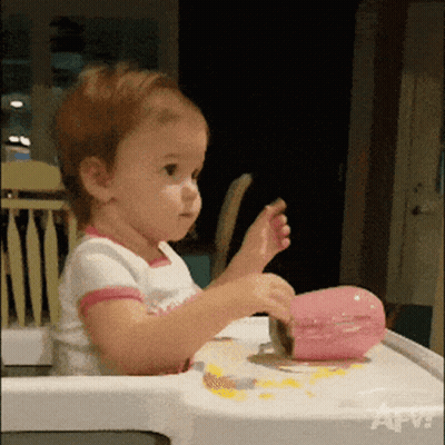 Little Girl In High Chair Playing With Pink Object GIF