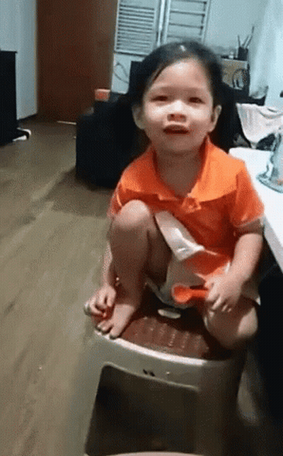 Little Girl In Orange Shirt Sitting On Stool GIF