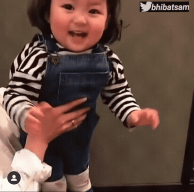 Little Girl In Overalls And Striped Shirt Being Held GIF