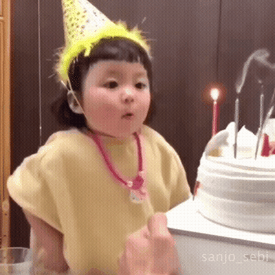 Little Girl In Party Hat Standing In Front Of Birthday Cake GIF