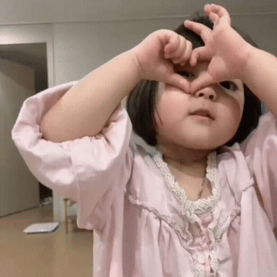 Little Girl In Pink Dress Making Heart With Hands GIF