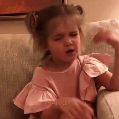 Little Girl In Pink Shirt Sitting On Couch Making Face GIF