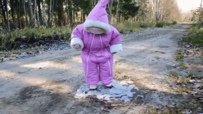 Little Girl In Pink Snow Suit Standing In Puddle GIF