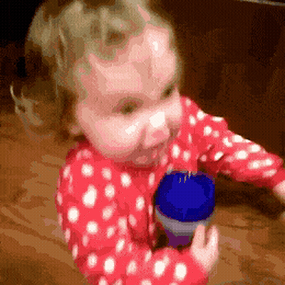 Little Girl In Red And White Polka Dot Pajamas Holding Blue Container GIF