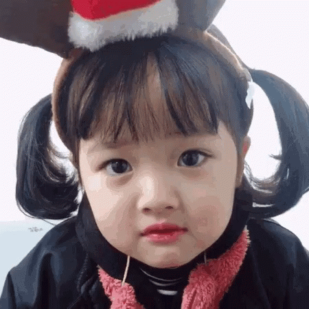 Little Girl In Reindeer Headband And Christmas Hat GIF