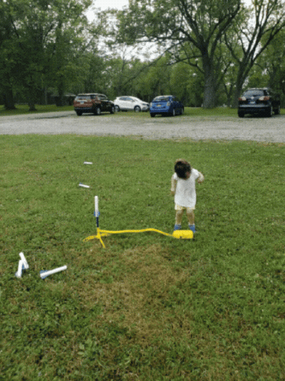Little Girl In White Dress Playing With Rocket GIF