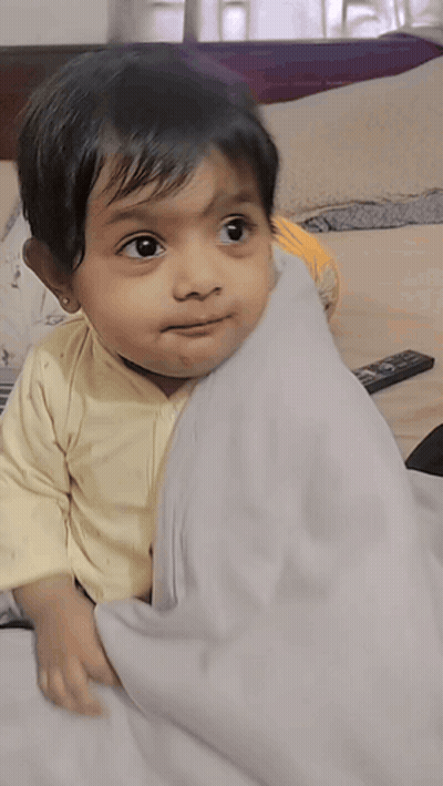 Little Girl Laying On Bed With Remote Control GIF