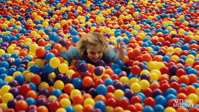 Little Girl Lying In Colorful Plastic Balls GIF