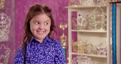 Little Girl Making Funny Face in Front of Tiara Shelf