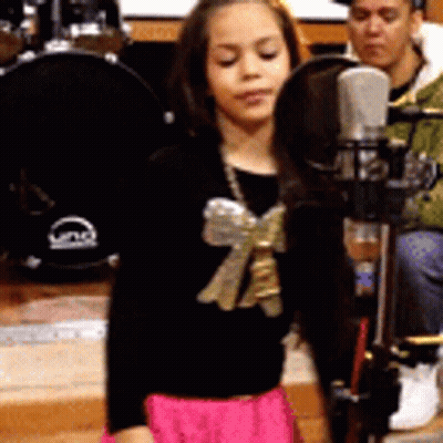Little Girl Singing Into Microphone With Bow GIF