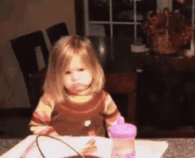 Little Girl Sitting At Table With Pink Bottle GIF