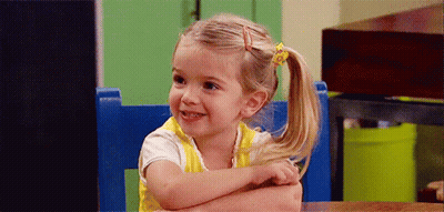 Little Girl Sitting In Blue Chair Arms Crossed Smiling GIF