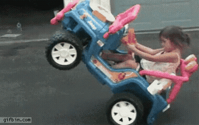 Little Girl Sitting In Blue Toy Car With Pink Steering Wheel GIF