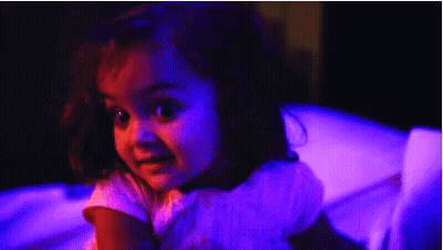 Little Girl Sitting In Chair With Purple Lights GIF