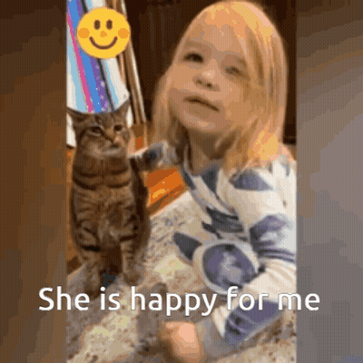 Little Girl Sitting Next To Happy Cat In Birthday Hat GIF