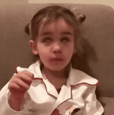 Little Girl Sitting On Couch Eating Candy Bar GIF