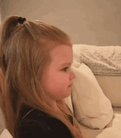 Little Girl Sitting On Couch Making Face GIF