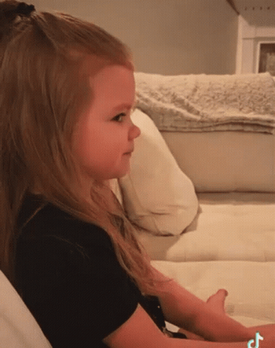 Little Girl Sitting On White Couch With TikTok Logo GIF