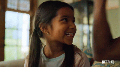Little Girl Smiling On Couch In Front Of Netflix Logo GIF