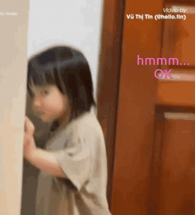 Little Girl Standing In Front Of Door Saying Hmm GIF