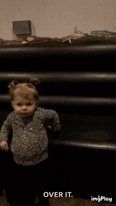 Little Girl Standing In Front Of Shelf GIF