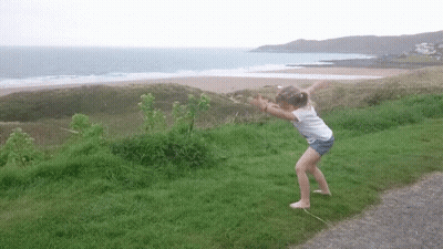 Little Girl Standing In Grass Near Ocean GIF