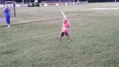 Little Girl Swinging Bat At Ball On Field GIF