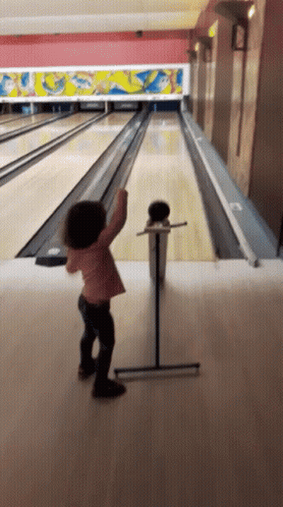 Little Girl Throwing Bowling Ball In Bowling Alley GIF