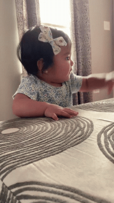 Little Girl With Bow Sitting On Bed GIF