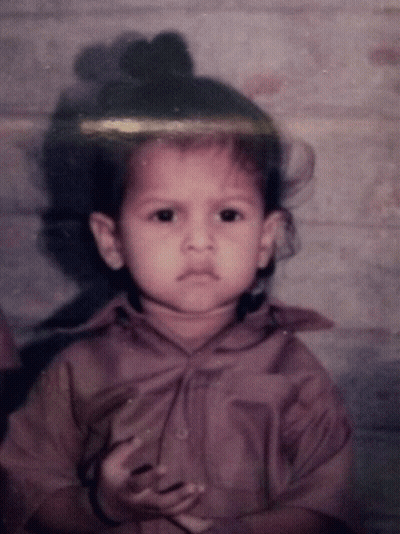 Little Girl With Bun On Head Looking At Camera GIF