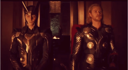Loki And Thor Standing Next To Each Other In A Dark Room GIF