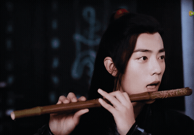 Long Hair Man Playing Flute Next To Sign A GIF