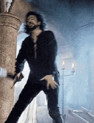 Long Hair Man With Beard Holding Gun Next To Pillar GIF