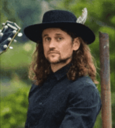 Long Haired Man In Black Hat Holding Guitar Willin GIF