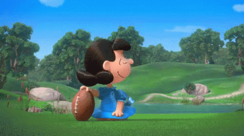 Lucy Brown Is Holding A Football While Charlie Brown Is Looking On GIF