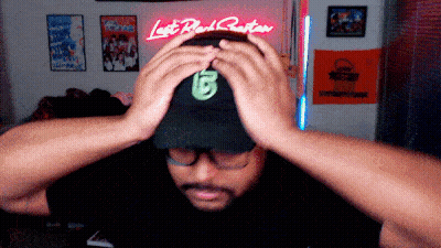 Man Adjusting Hat In Front Of Lost Black Gator Neon Sign GIF