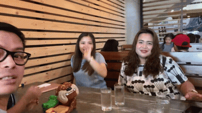 Man And Two Women At Table With Stuffed Monkey GIF
