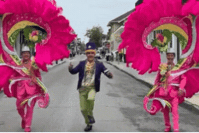 Man And Two Women In Pink Costumes Walking Down Street GIF