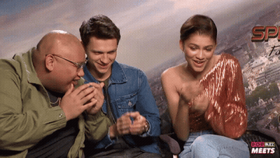 Man And Two Women Laughing In Front Of Pop Buzz Meets Sign GIF