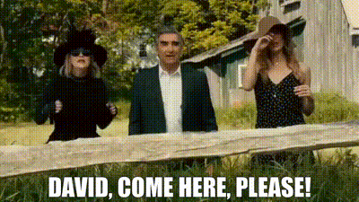 Man And Two Women Standing By Fence With Sign Saying David Come Here Please GIF